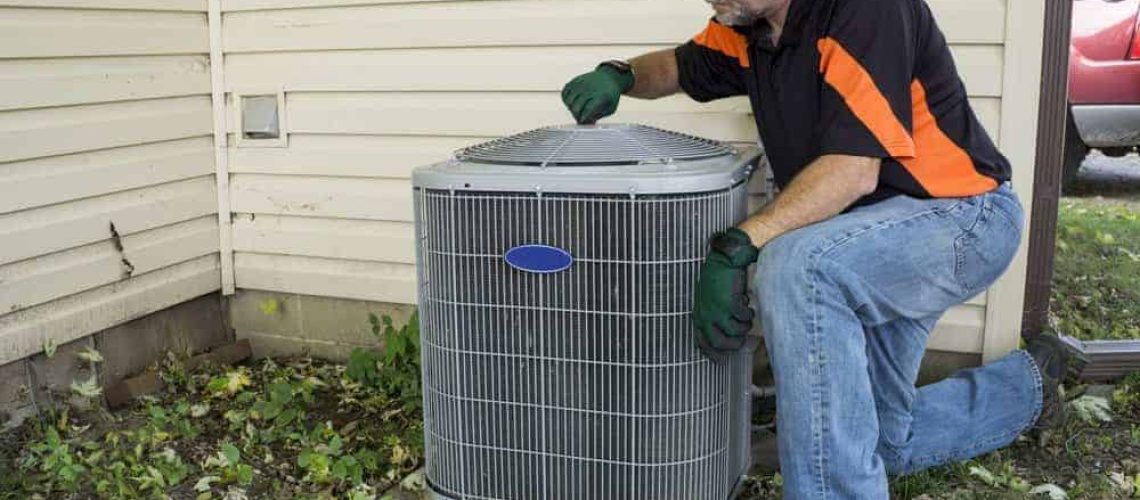 Repairman tightening fan shroud on outside air conditioning unit