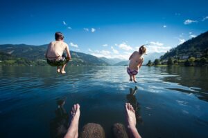 two kids jumping into a lake